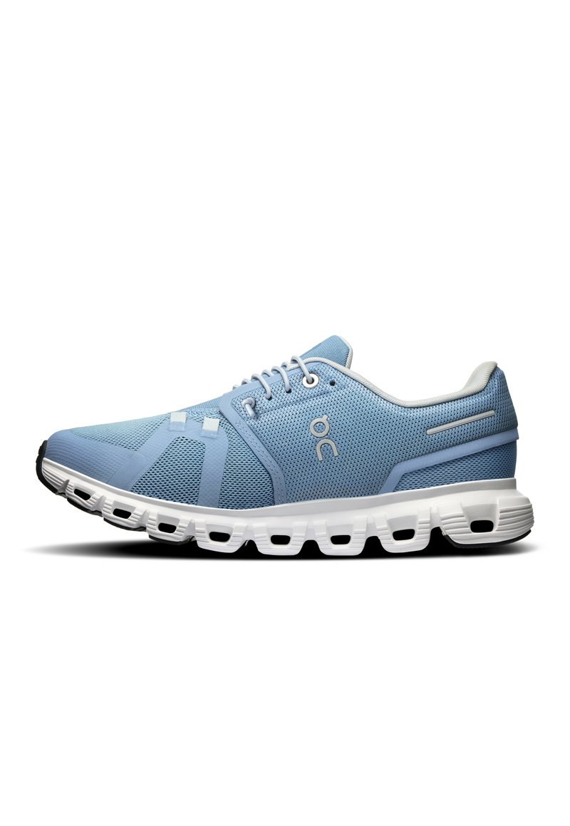 Scarpe da ginnastica azzurro chiaro con tomaia in rete, dotate di una suola bianca con ritagli distintivi e dettagli cuciti.