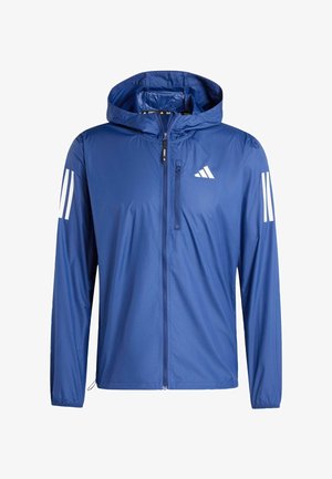 Blauwe lichte capuchonjas met ritssluiting aan de voorkant, borstzak met rits en wit drie-strepenlogo op mouwen en borst.