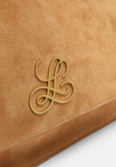 Tan suede material with neat stitching and a gold intertwined initials logo detail on a bag's surface.