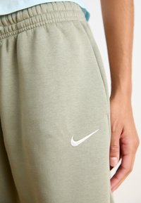 Kerged rohelised Nike dressipüksid elastse vöökohtaga, mille alumises osas on valge logo, valmistatud pehmest puuvillasegusest materjalist.