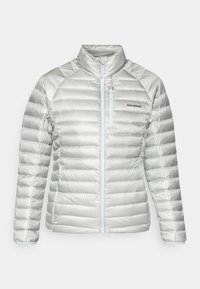 Ezüst pufferek jacket vízszintes steppeléssel, magas gallérral, elülső cipzárral és cipzáras mellzsebbel. Bal oldalán logó található.