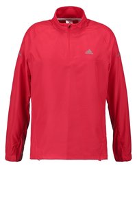 Chaqueta deportiva roja de Adidas de manga larga con media cremallera, cuello alto y logotipo reflectante en el pecho y en las mangas.
