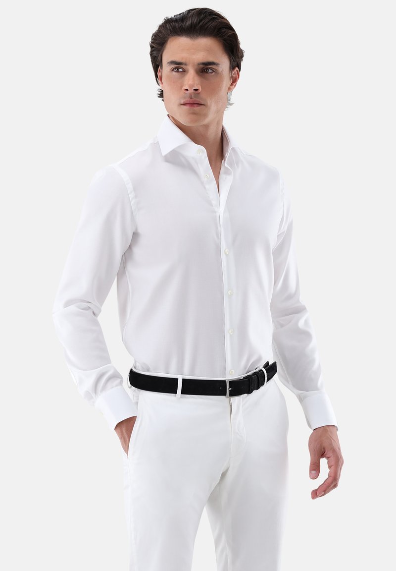 Weißes Hemd mit langen Ärmeln und einem Button-Down-Kragen. Glatter, leichter Stoff, schmale Passform, kombiniert mit einer weißen Hose und einem schwarzen Gürtel.