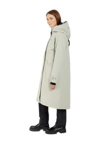 Light gray waterproof long coat with a hood, featuring a zip closure, side pockets, and black accents. Paired with black pants and boots.