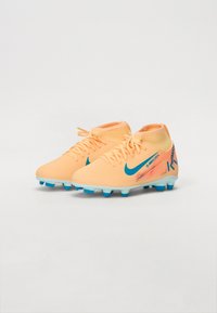 Cizme de fotbal Nike portocalii și albastre, cu un design aerodinamic, un superior texturat și cu cuișoare modelate pentru tracțiune pe suprafețe de iarbă.
