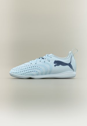 Light blue Puma indoor soccer shoe with black logo, textured upper, laces, and pull tab on a neutral background.