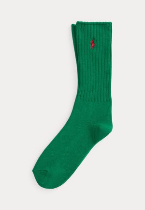 Chaussette verte côtelée à hauteur de mollet avec un petit logo rouge brodé représentant un cheval et son cavalier près du haut du bord-côte.