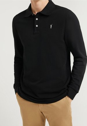 Schwarzes Langarm-Polohemd mit einem knöpfbaren Kragen, versehen mit einem kleinen silbernen Golfer-Logo auf der linken Brust und glatter Stofftextur.