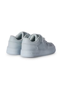 Un paio di sneaker basse grigie chiare con fasce in velcro e logo Champion sul lato e sulla suola, viste da dietro e angolate a destra.
