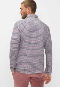 Camicia da uomo a maniche lunghe con bottoni, in un motivo a quadri blu, rosso e bianco. Presenta un colletto e polsini con bottoni. Tessuto in cotone.