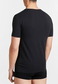 Maglietta nera a maniche corte realizzata in cotone morbido, con scollo rotondo e design aderente, vista dal retro. Costruzione semplice e solida.