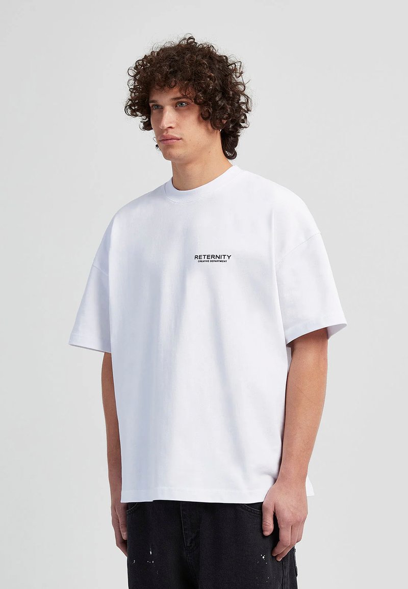 Weißes, übergroßes T-Shirt mit rundem Ausschnitt und kurzen Ärmeln. Verfügt über schwarzen Drucktext auf der Brust. Das Material wirkt glatt und leicht.