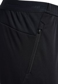 Schwarze Sportshorts mit texturiertem Bund und einer Reißverschlusstasche an der Seite für sicheren Stauraum.