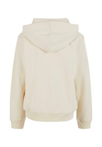 Krämfärgad hoodie med mjuk textur, avslappnad passform, ribbade ärmslut och nederkant. Sömmar synliga på baksidan.