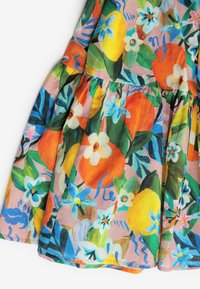 Robe en coton à motifs floraux avec des fleurs orange vif, jaune et bleues sur un fond rose. Elle présente une jupe plissée et une texture lisse.