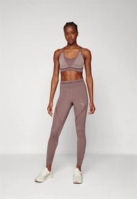 Urheiluliivit ja leggingsit himmeässä mauvessa. Liiveissä V-pääntie; leggingseissä kaarevat sauma-yksityiskohdat. Valmistettu joustavasta, kevyestä materiaalista.