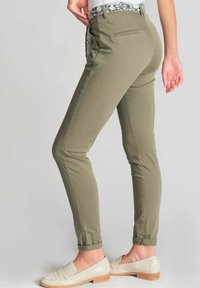 Slim-fit olijfgroene broek met een bloemenpatroon op de tailleband, voorzien van achterzakken en omgerolde mouwen. Gemaakt van een zachte, gestructureerde katoenmix.