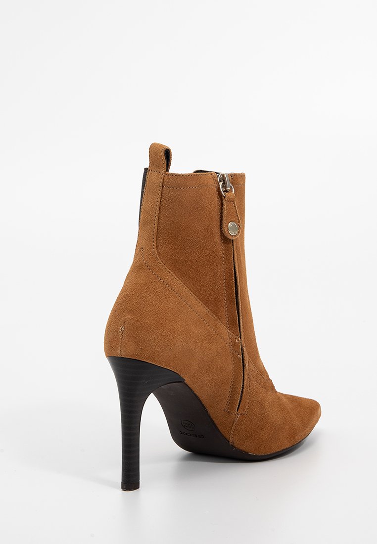 Stivaletto in suede color tan con punta affusolata, zip laterale e tacco sottile nero. Presenta una texture liscia e accentuazioni hardware minime.