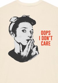 Krémové tričko s černobílým grafikou osoby s čelenkou a červeným textem "OOPS I DON'T CARE."