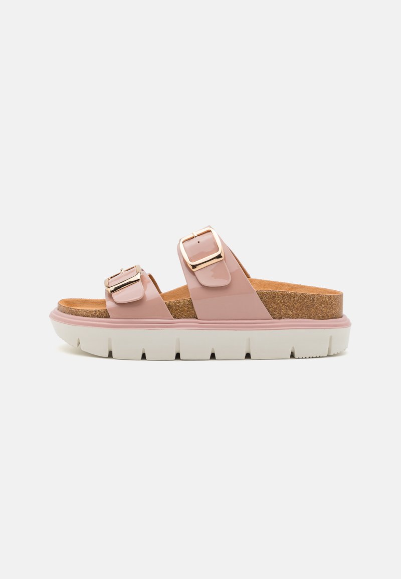 Sandales roses à deux brides avec une finition brillante, boucles dorées, semelle en liège et une semelle blanche épaisse avec des détails striés.