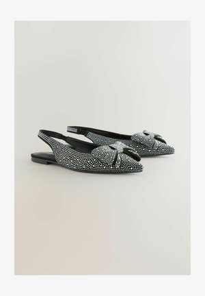 Mustad musta slinga-bakiga tasud, millel on terav varvas, kaunistatud valgete nööpidega ja esiosas dekoratiivne kaares. Sile tekstuur madala kontsaga.