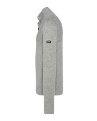 Szary sweter robiony na drutach z wysokim kołnierzem, długimi rękawami i czarną łatą z logo na lewym rękawie. Miękka tekstura, dopasowany krój.