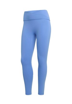 Siniset urheiluleggingsit, joissa on korkea, ristiin menevä vyötärönauha. Valmistettu pehmeästä, joustavasta kankaasta, istuvalla mallilla ja ilman näkyviä kuvioita.