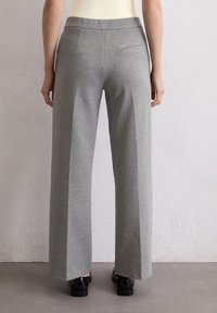 Helle graue, weit geschnittene Hosen aus einem weichen, dehnbaren Material. Sie haben einen glatten Taillenbund und zwei Gesäßtaschen.