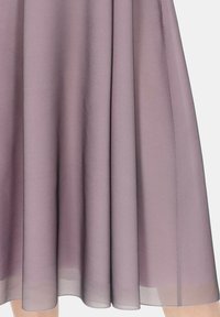 Fioletowa plisowana spódnica wykonana z lekkiego materiału, charakteryzująca się zwiewnym krojem i miękką teksturą, z delikatnym połyskiem na dole.