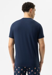 Marineblauwe t-shirt met korte mouwen en een ronde hals, met een gladde textuur en een eenvoudig ontwerp, gecombineerd met een patroonjoggingbroek.