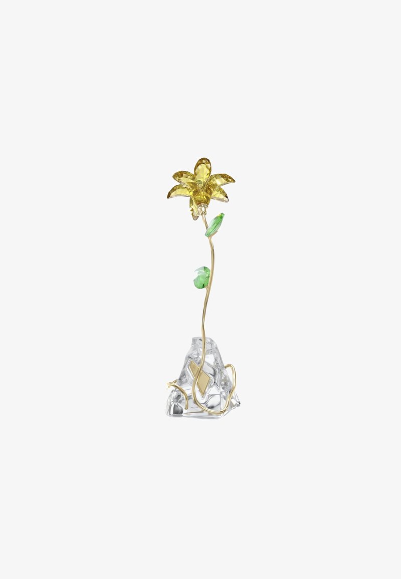 Flor de metal en tono dorado con pétalos de cristal amarillo y acentos de hoja verde sobre una base clara texturizada que se asemeja a una gema.