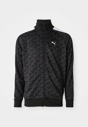 Zwarte ritssluitingjack met een herhalend logo-patroon, ribbelmanchetten en -zoom, en witte accenten op de schouders. Gemaakt van een gladde stof.