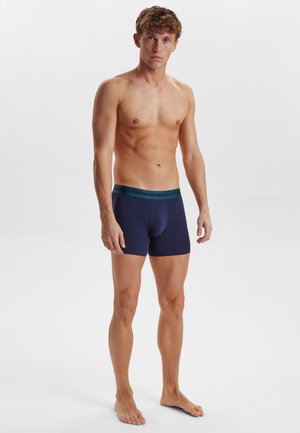 Marineblå boxer shorts med en grønstribet talje, lavet af et glat, strækbart stof, med et tætsiddende design og minimale sømme.