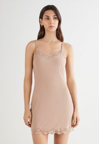 Vestido camisón nude de canalé con encaje en el escote y el dobladillo, tirantes finos ajustables, textura suave y diseño entallado.
