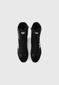 Černé kotníkové tenisky s texturovaným semišovým a síťovaným designem. Mají tkaničky, zipové zapínání a bílý akcentní pruh na boku.