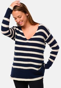 Pull rayé bleu marine et blanc avec un décolleté en V profond et des manches longues, fabriqué en matériau tricoté doux, avec une coupe décontractée et des poches latérales.