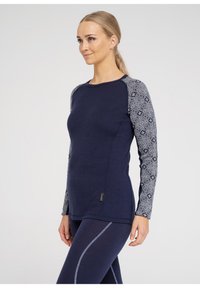 Marineblå langærmet top med mønstrede grå �ærmer, rund halsudskæring, slim fit og diskret sømdetalje; kombineret med matchende leggings.