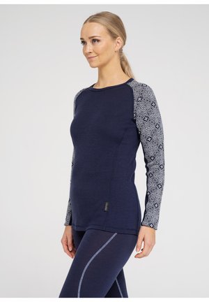 Marineblå langærmet top med mønstrede grå ærmer, rund halsudskæring, slim fit og diskret sømdetalje; kombineret med matchende leggings.