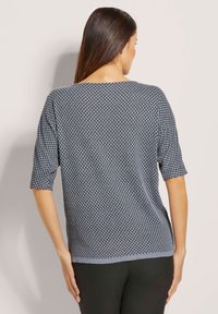 Korte mouwen marineblauw trui met een textuurpatroon, voorzien van een brede halslijn en een relaxte pasvorm, gedragen met een zwarte broek.