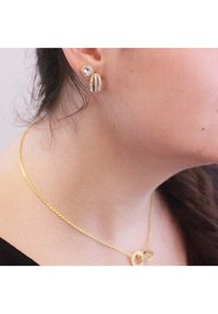 Orecchini placcati in oro con perno circolare e pendente, decorati con strass trasparenti. Collana in catena dorata con pendente circolare.