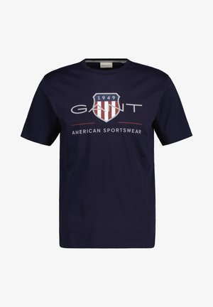 Mornarsko modra bombažna majica s krojnim ovratnikom, s grafičnim dizajnom, ki vsebuje zaščitni znak in besedilo "GANT" ter "AMERICAN SPORTSWEAR."