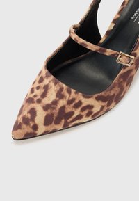 Visoke potpetice s leopard uzorkom i izduženim vrhom, napravljene od mekog materijala, s crnim uloškom i remenom oko gležnja s kopčom u zlatnoj boji.