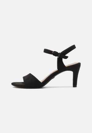 Sandale en suède noir avec un design à bout ouvert, une bride à la cheville et un talon effilé de 7 cm. Présente une texture mate et un style minimaliste.