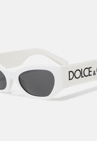 Hvite solbriller med en elegant katteøyefasong, grå linser og en dristig "DOLCE & GABBANA"-logo på sidene. Matt finish med jevn tekstur.