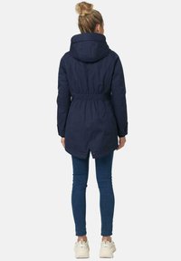 Navy blue parka jacket with a drawstring waist, hood, and elastic cuffs, featuring a longer back hem and a smooth fabric texture.
