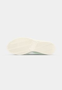 Suola di sneaker in gomma bianca testurizzata con tasselli a zigzag; il lato è verde chiaro con un accento grigio, adatto a un design sportivo.
