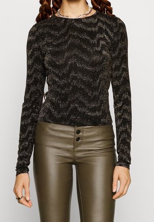 Sort langærmet top med tekstureret, glitrende design. Kombineret med højtaljede, tætsiddende olivengrønne bukser med tre knaplukninger.