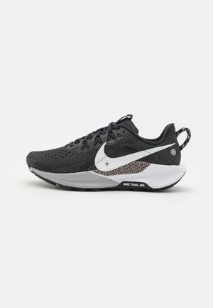 Baskets de sport noires avec une tige en maille texturée, un swoosh Nike blanc, une semelle foncée et des accents gris. Conçues pour la course en sentier avec une adhérence solide.