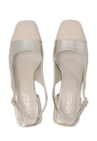 Beige and gold slingback heels with a square toe and cut-out sides, featuring a strap and logo on the insole. Elegant and stylish design.