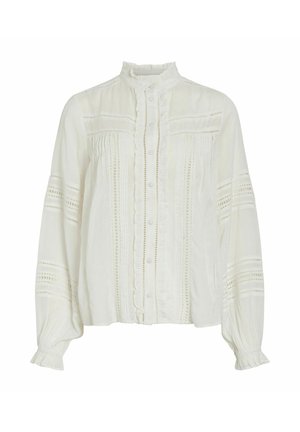 Blusa bianca con maniche lunghe, colletto alto arricciato, chiusura frontale con bottoni e dettagli di pizzo intricate lungo il petto e le maniche. Tessuto di cotone morbido.